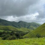 Scenic view of the Kudremukha peak in Karnataka's Western Ghats, featuring rolling green hills, mist-covered valleys, and dense forests during a trek