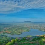 A serene sunrise over Makalidurga, illuminating the rocky terrain and dense vegetation below
