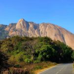 Scenic view of Savandurga Hill, a towering monolithic rock formation near Bangalore, India, surrounded by lush greenery and popular for trekking adventures.